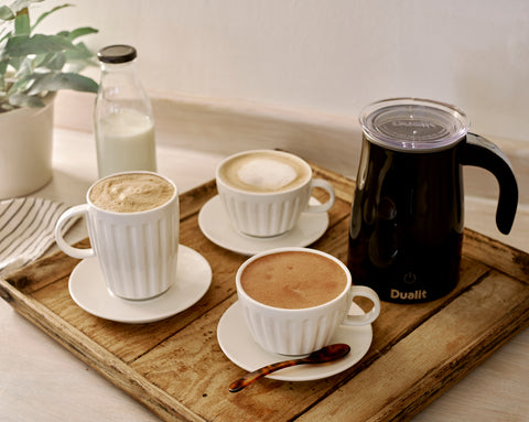                                                                             Coffees on a wooden tray with a milk bottle and black Dualit chocolate maker.                                                                     